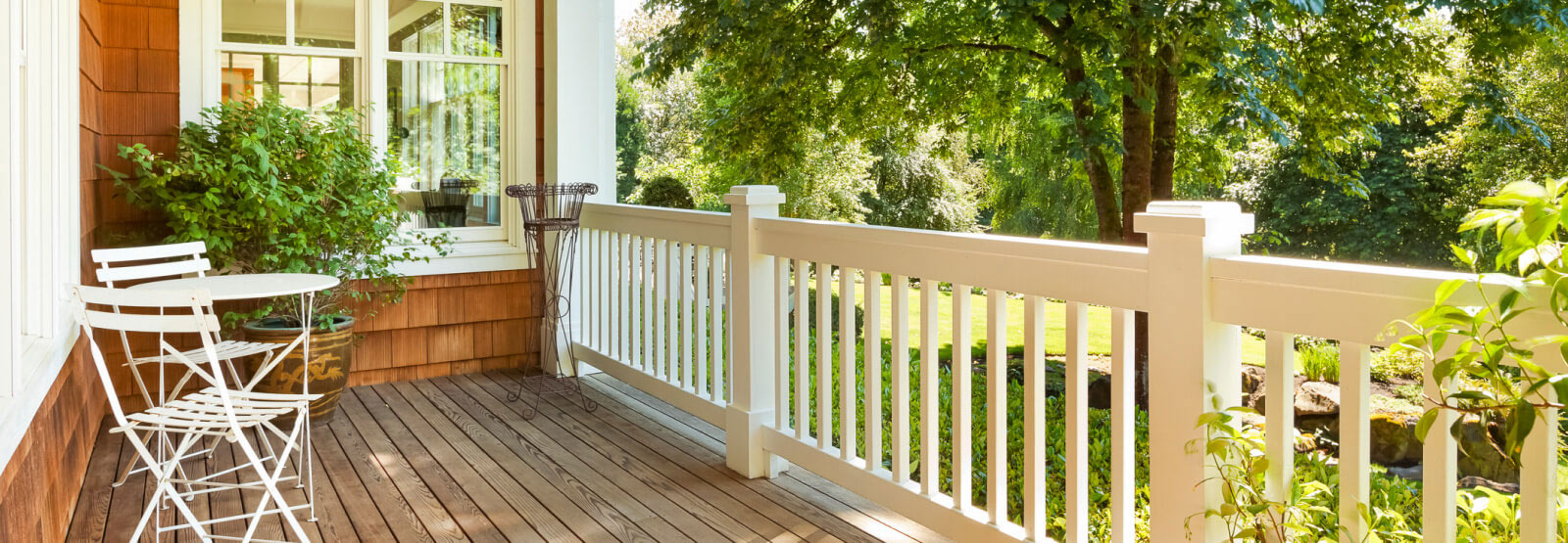 A neatly maintained front porch with a lush yard in the background