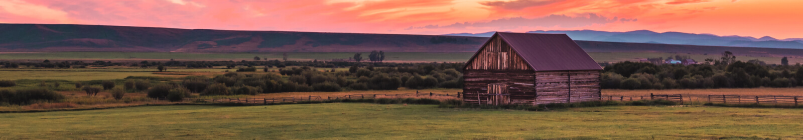 A landscape shot of an old barn in a rural field